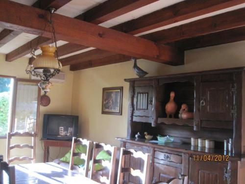 a dining room with a table and a tv at Les Chênes 2 - cadre verdoyant in Eugénie-les-Bains