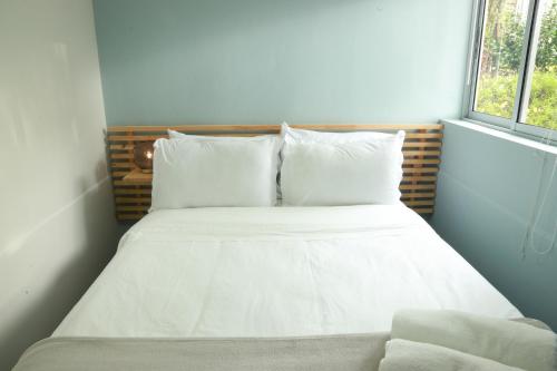 a bed with white sheets and pillows next to a window at Hotel Bania travels in Guatapé