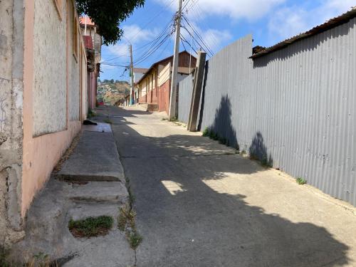 an empty alley with a white building and a fence at Hostal brons in Valparaíso