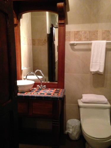 a bathroom with a sink and a toilet and a mirror at Roka Plaza Hotel Boutique in Ambato