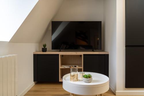 een woonkamer met een tv en een witte tafel bij Le Chirac 5 T2 Centre Historique Rodez in Rodez