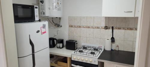 cocina pequeña con nevera blanca y fogones en Depto en Tandil Garibaldi 388 en Tandil