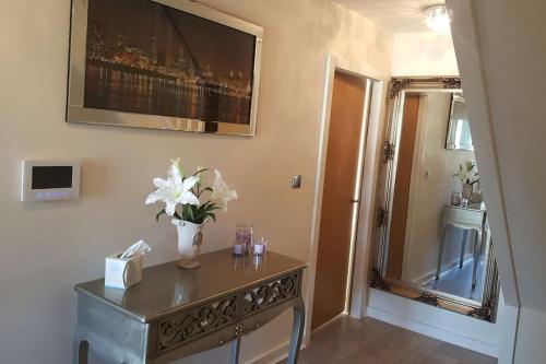 a room with a table with a vase of flowers on it at Large 6 bedroom duplex - perfect for large family in Liverpool