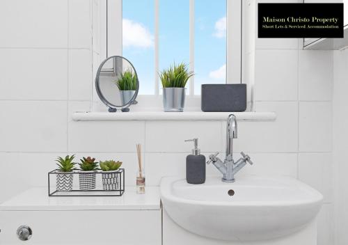 a bathroom with a sink and a window with potted plants at Kirkwall 1Bedroom Apt Sleeps 4 with Wifi & Lesiure By Maison Christo Property Short Lets & Serviced Accommodation in London