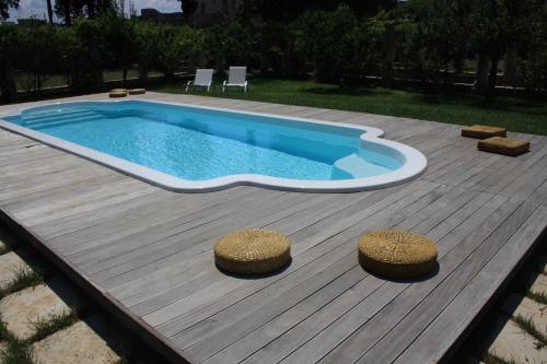a swimming pool on a wooden deck with two stools at Castello di Casamassella - Marea Stays Collection in Casamassella