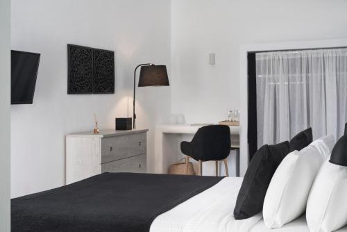 1 dormitorio con cama, escritorio y silla en Mr and Mrs White Santorini en Oia