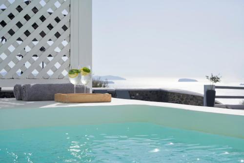 two glasses of wine sitting next to a swimming pool at Mr and Mrs White Oia - Santorini in Oia