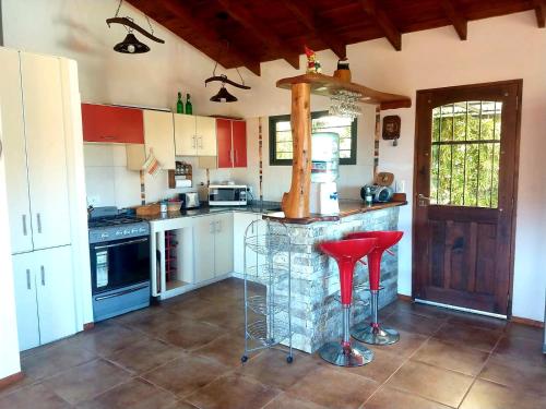 cocina con encimera y 2 taburetes rojos en MiraSierras -casas vacacionales- en Villa General Belgrano