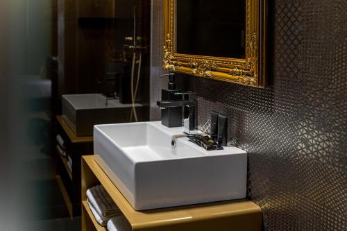 een badkamer met een witte wastafel en een spiegel bij Plebiscito Boutique Rooms in Napels
