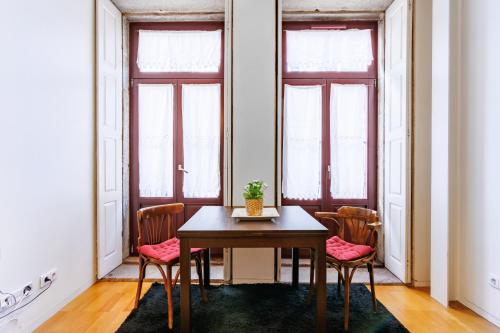 una mesa y sillas en una habitación con ventanas en Studios Cedofeita, en Oporto