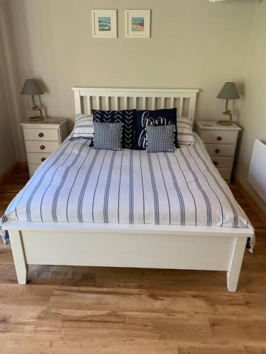 uma cama branca num quarto com duas mesas de cabeceira em The Piggery at the Cottage em Wool