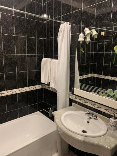 a black tiled bathroom with a sink and a tub at Casa De Cha Prazeres in Prazeres