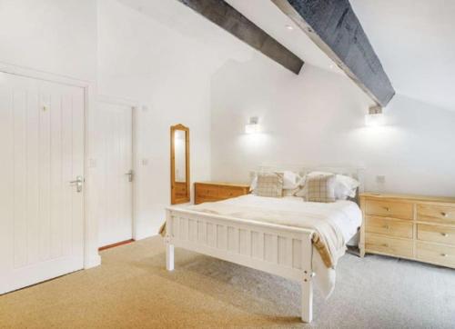 a white bedroom with a bed and a wooden dresser at The Cottages at Ivy Farm by Charles Alexander Short Stay in Lytham St Annes