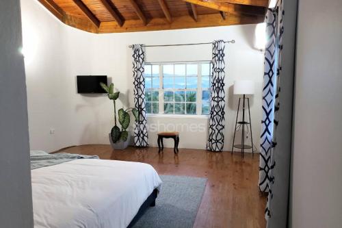 una camera con un letto e una grande finestra di Farmhouse Estate 30mins from Ocho Rios/Kgn a Knowles