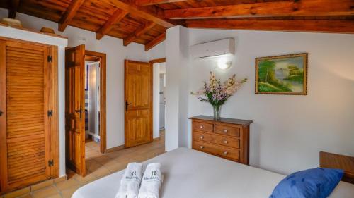 a bedroom with a bed and a vase of flowers on a dresser at Villa Evelyn Gaucín by Ruralidays in Gaucín
