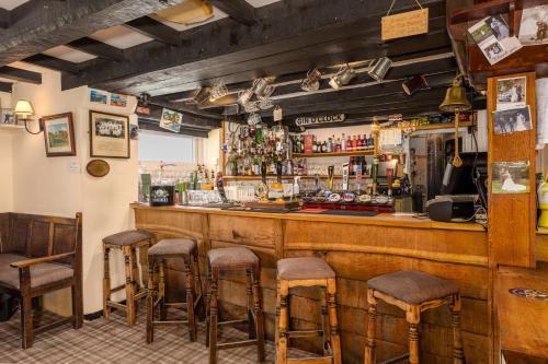 a bar with stools in a room with a counter at Bower House Inn in Eskdale