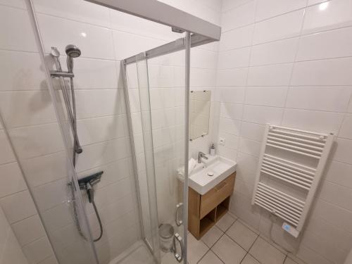 a white bathroom with a shower and a sink at La Cabane de l'Océan à 100 m de la plage in Mimizan-Plage