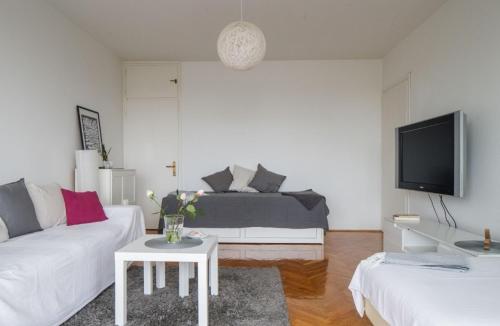 a living room with a white couch and a tv at Relax Central Apartment in Zagreb