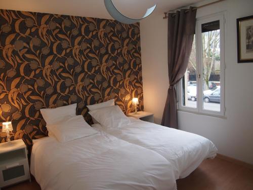 - une chambre avec un lit blanc et un papier peint floral dans l'établissement L'Escale 80, à Amiens