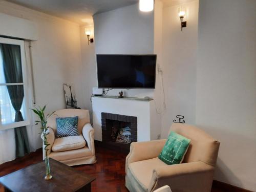 sala de estar con 2 sillas y chimenea en Departamento Mendoza en Mendoza
