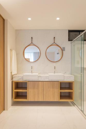 a bathroom with two sinks and two mirrors at Acqua Residences Luxury Collection in Cabedelo