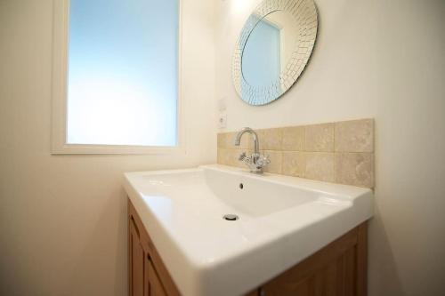 ein Badezimmer mit einem weißen Waschbecken und einem Spiegel in der Unterkunft Grand studio lumineux calme au coeur des vignes in Montaud