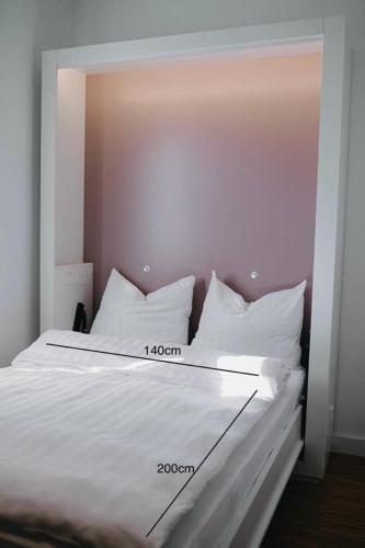a bed with white sheets and white pillows at Maximilian Studios in Speyer