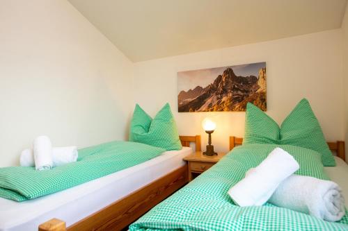 2 Betten in einem Zimmer mit grüner und weißer Bettwäsche in der Unterkunft Haus Herz in Haus im Ennstal