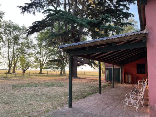 a pavilion with chairs and a tree in a field at Casa de campo “Los Ombues” in Suipacha