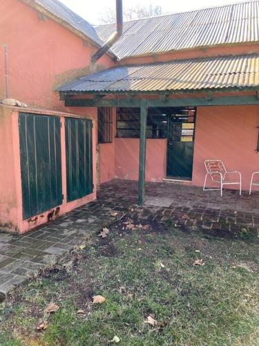 a house with a chair sitting outside of it at Casa de campo “Los Ombues” in Suipacha
