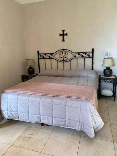 a bedroom with a bed with a cross on the wall at Casa de campo “Los Ombues” in Suipacha