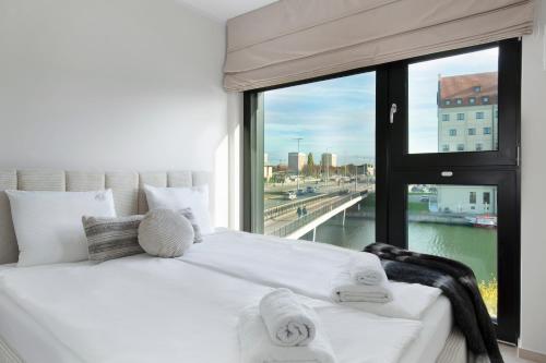 a white bed in a room with a large window at Elite Apartments Rezydencja Wintera in Gdańsk