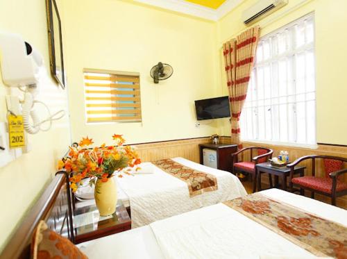 a hotel room with two beds and a vase of flowers at Lam Dat Hotel in Ninh Binh