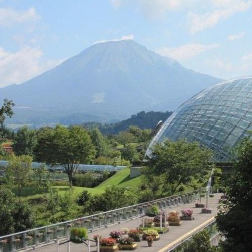 a large glass building with a mountain in the background at Kyukamura Oku-Daisen in Daisen