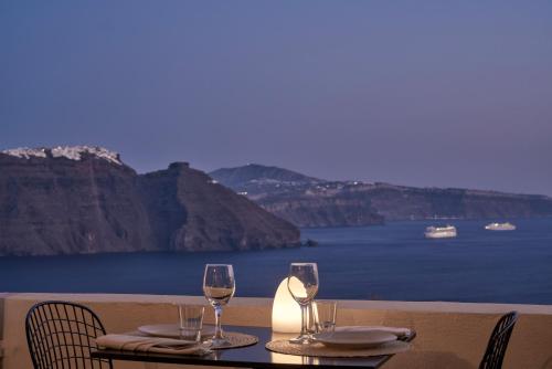 a table with two wine glasses on top of it at Mr and Mrs White Oia - Santorini in Oia