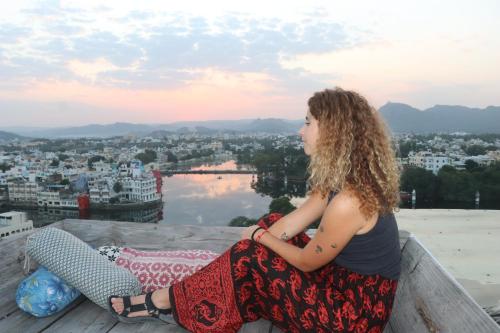 a woman sitting on a ledge looking out over a city at Bunkyard Hostel in Udaipur