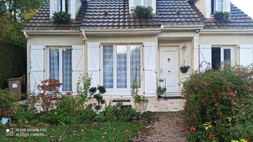 a house with a white door and some flowers at Chambre d hôte à 20 min de VERSAILLES in Le Mesnil-Saint-Denis