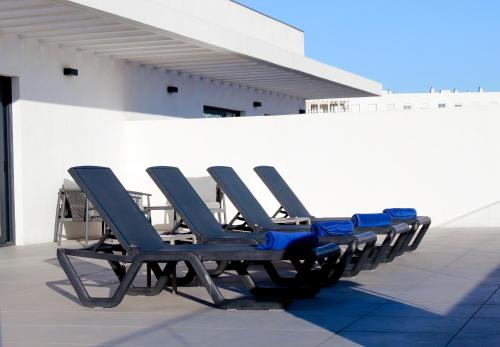 a row of blue chairs sitting on the side of a building at Aqua Apartments Bellamar, Marbella in Marbella