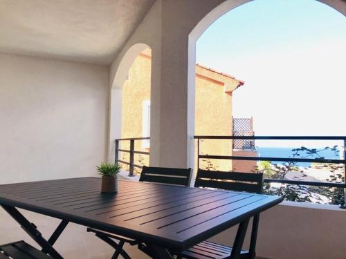 une table en bois avec une plante en pot sur un balcon dans l'établissement MONTICELLO - L'ÎLE-ROUSSE APPARTEMENT BORD DE MER 3 Pièces 4 Personnes, à Monticello