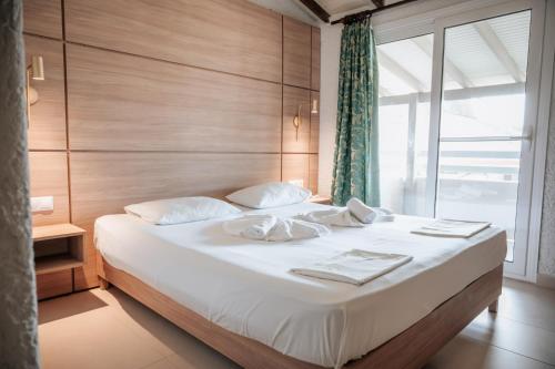 een slaapkamer met een bed met witte lakens en een raam bij Hotel Platon Beach in Olympiakí Aktí