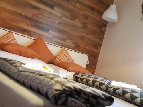 a bed with orange pillows and a wooden headboard at Twins in Hurbanovo