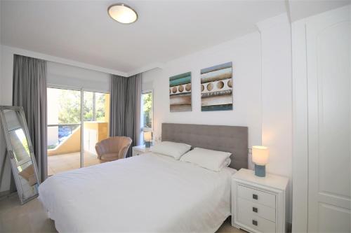 Un dormitorio blanco con una cama blanca y una ventana. en Estepona Port Apartment SOL, en Estepona