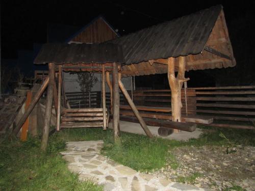 a wooden building with a roof on the grass at Nota Bene Mykulychyn in Mykulychyn