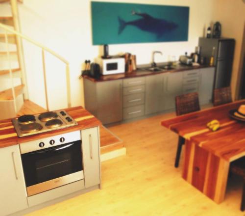 a kitchen with a stove and a table with a shark on the wall at Waterside Apartment in Gansbaai