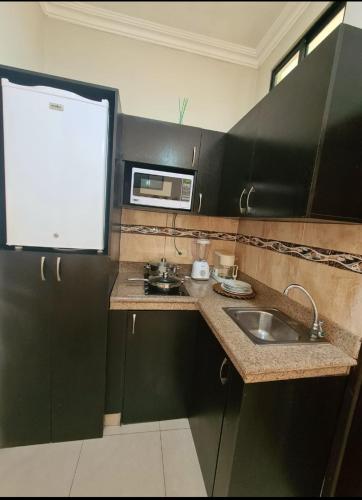 a small kitchen with a sink and a microwave at Suite 3B Empresarial 10Min Malecón Universidad in Guayaquil