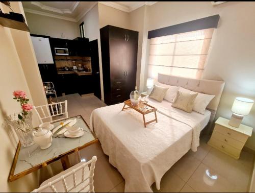 a bedroom with a white bed and a table with a table at Suite 3B Empresarial 10Min Malecón Universidad in Guayaquil