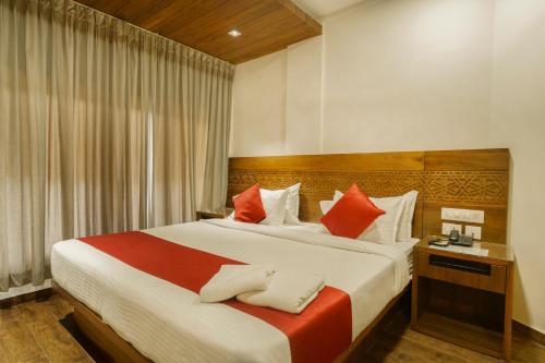 1 dormitorio con 1 cama grande con almohadas rojas y blancas en KINGS CALICUT, en Kozhikode