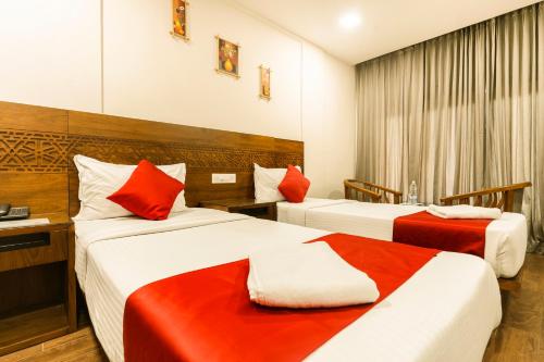 two beds in a hotel room with red and white at KINGS CALICUT in Kozhikode