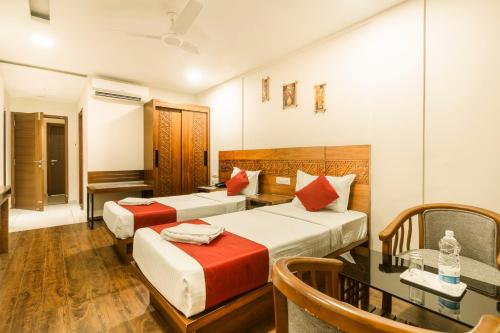 a hotel room with two beds and a table at KINGS CALICUT in Kozhikode