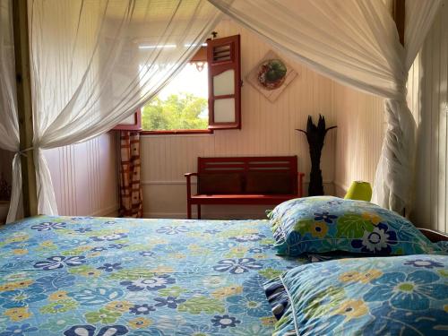 a bedroom with a bed with a blue comforter and a window at LE DOMAINE DE LA VALLEE in Le Morne Rouge